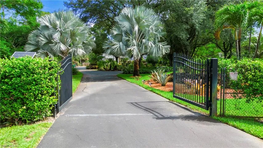View of asphalt driveway with a gate and a gated entry