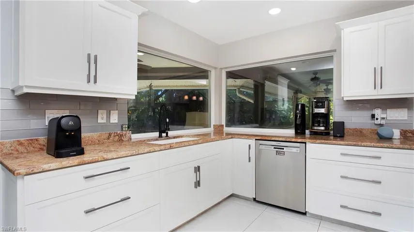 Kitchen featuring stainless steel dishwasher, tasteful backsplash, white cabinetry, and a ceiling fan