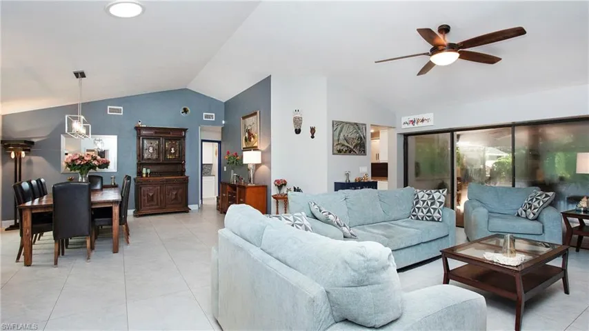 Living room with lofted ceiling, a ceiling fan, and light tile patterned flooring