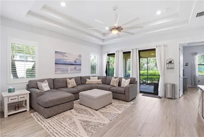 Great room with tray ceilings, wood plank tile flooring, and an open concept layout.