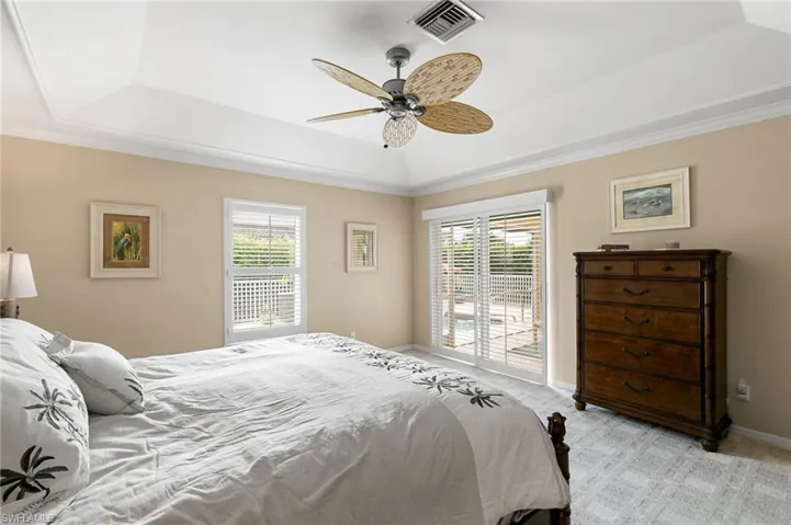 Master bedroom with slider access to outside, ceiling fan, and a tray ceiling