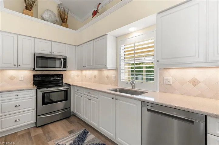 Kitchen stainless steel appliances, sink, and white cabinetry