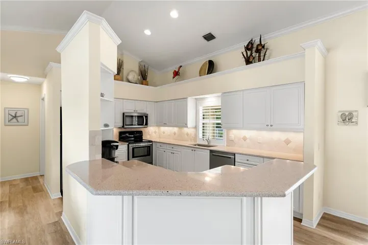Kitchen featuring light countertops, kitchen peninsula, crown molding, appliances with stainless steel finishes.