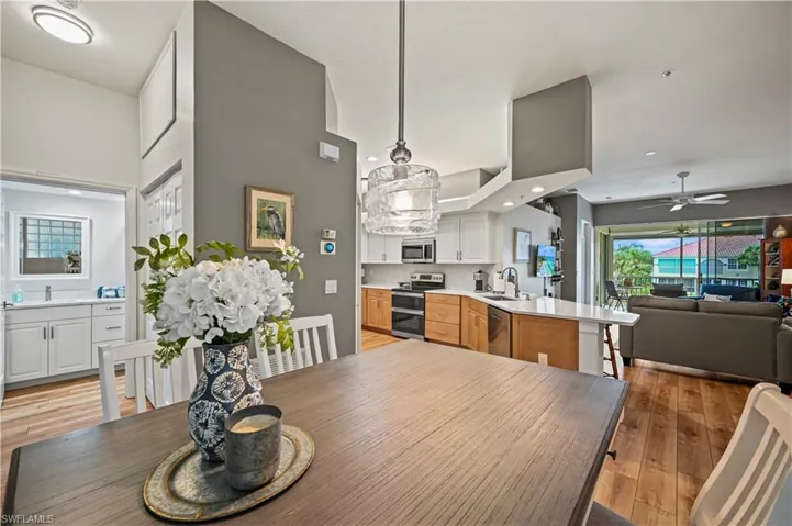Dining area with sink, ceiling fan, a towering ceiling, and light wood-type flooring
