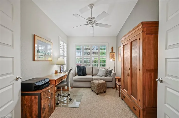 Carpeted office space featuring ceiling fan and vaulted ceiling