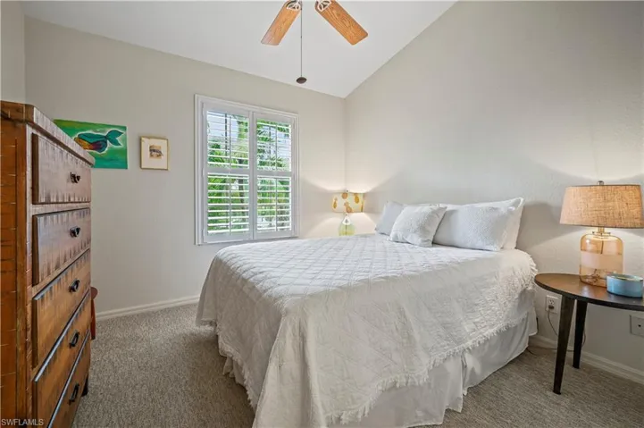 Carpeted bedroom featuring ceiling fan and lofted ceiling