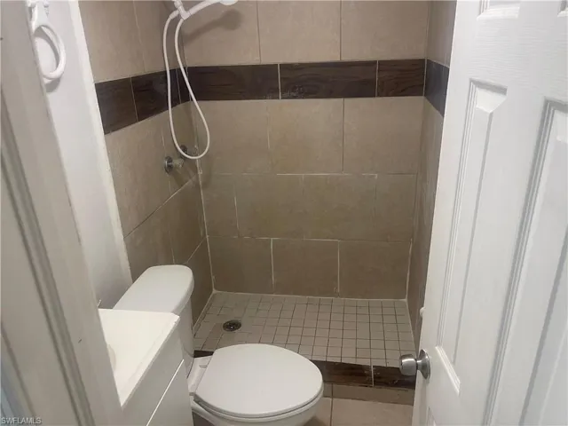 Bathroom with a tile shower, vanity, and toilet