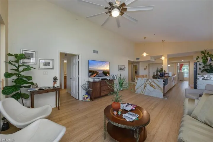 Living room featuring light wood-style flooring, high vaulted ceiling, and a ceiling fan