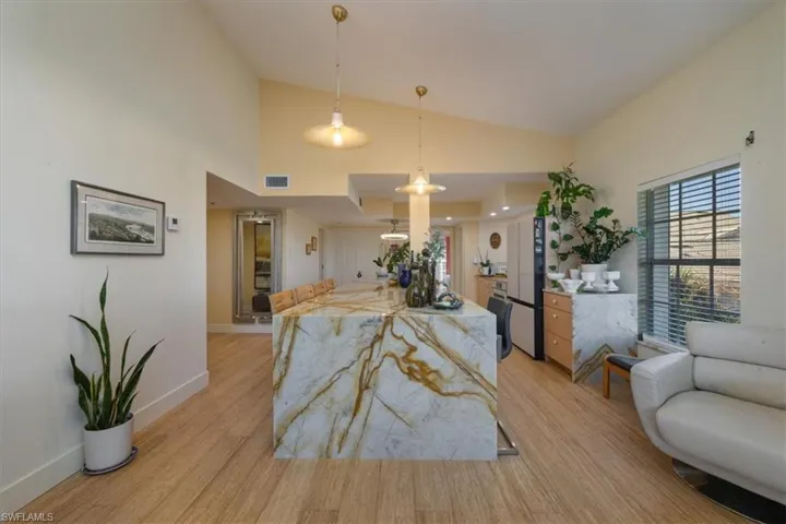Kitchen with hanging light fixtures, open floor plan, light stone countertops, light wood-style floors, and recessed lighting