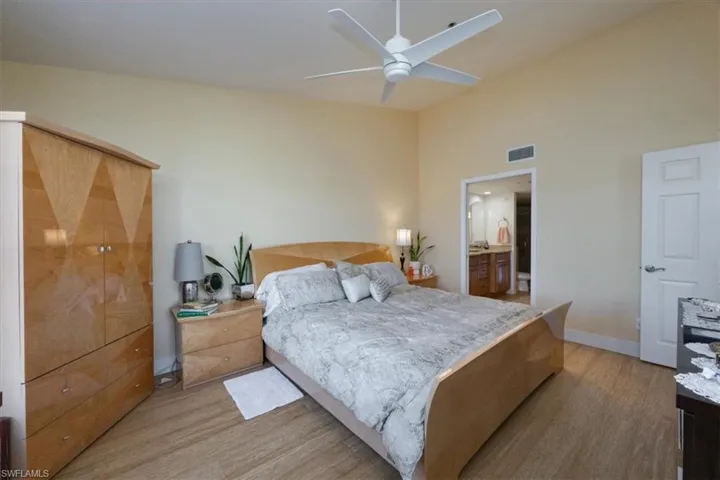 Bedroom featuring light wood-style floors, ensuite bathroom, and a ceiling fan