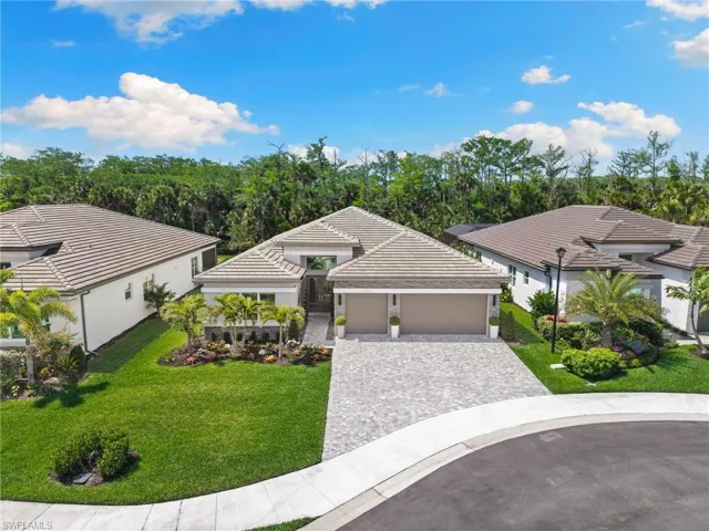 View of front of house with decorative driveway, a garage, a front yard, and stucco siding