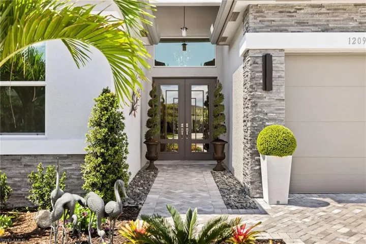 View of exterior entry featuring french doors, stone siding, and stucco siding