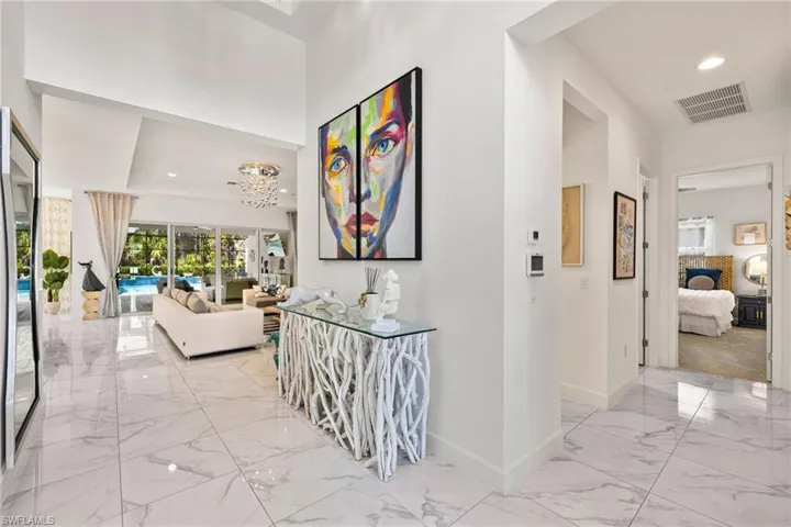Hallway with light marble finish flooring and suspended lighting