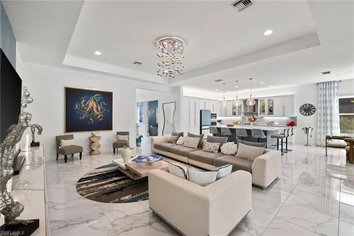 Living area featuring a raised ceiling and suspended lighting