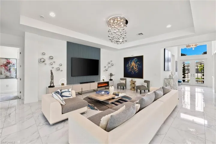 Living area with a chandelier, a tray ceiling, and french doors