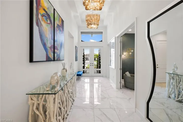 Foyer featuring hanging lights, a high ceiling, french doors, and light marble finish flooring
