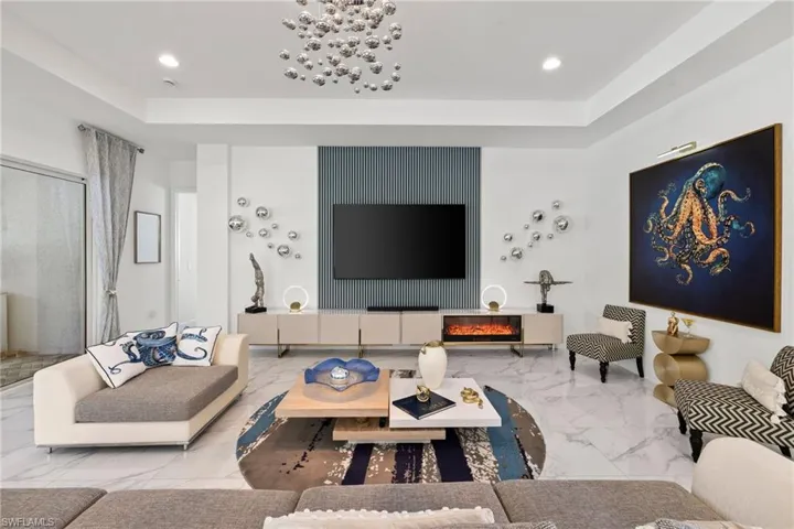 Living area with an accent wall, a tray ceiling, recessed lighting, and marble tiled flooring