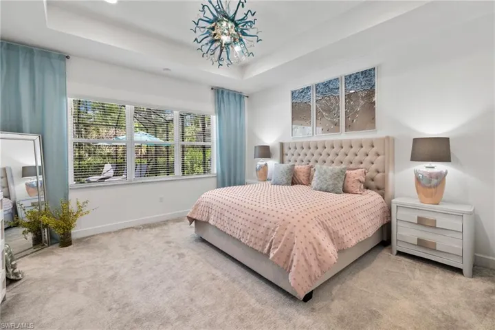 Primary bedroom featuring a tray ceiling and a chandelier