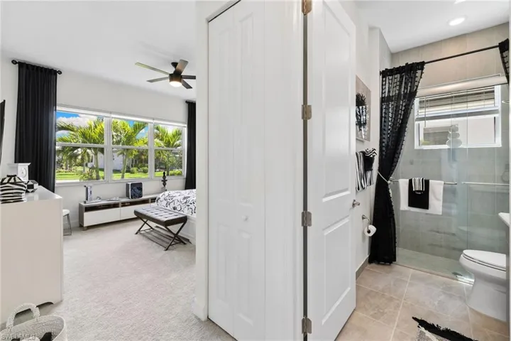 Bathroom featuring a shower stall, vanity, ceiling fan, and a closet