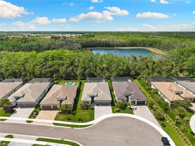 Aerial view of residential area with a large body of water and a forest