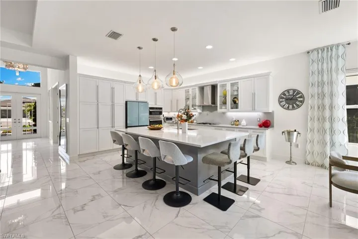 Two tone kitchen with plenty of natural light, glass fronted cabinets, french doors, a kitchen breakfast bar, and dual tone cabinetry