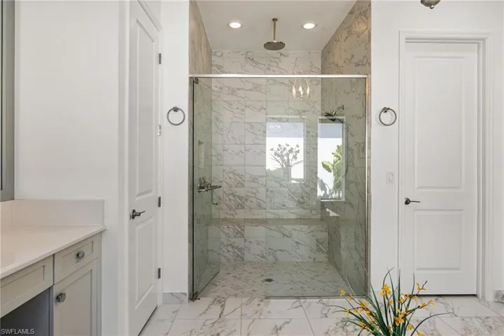 Primary Bathroom featuring a marble finish shower, vanity, light marble finish floors, recessed lighting, and a closet