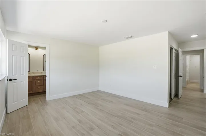Unfurnished bedroom with light wood-style flooring and connected bathroom