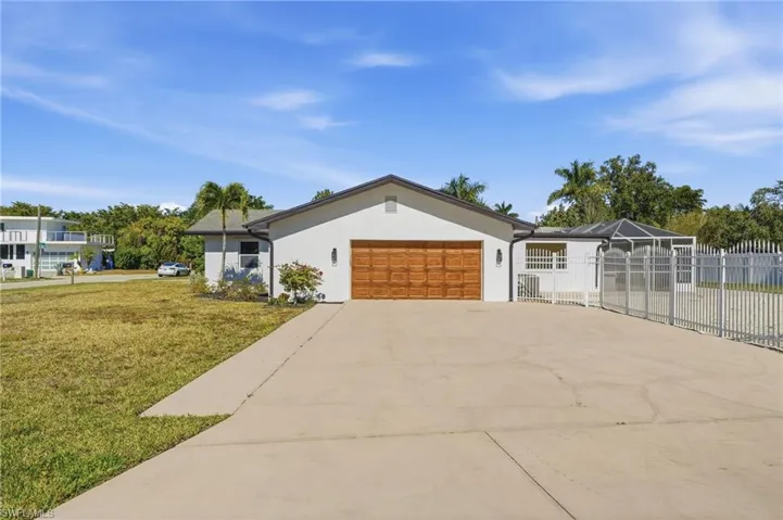 Ranch-style home featuring concrete driveway, stucco siding, glass enclosure, and a garage