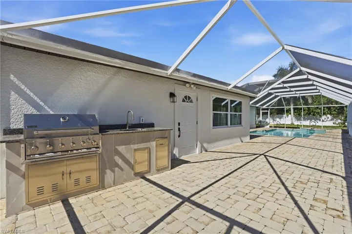 View of patio / terrace with a sunroom, exterior kitchen, a lanai, and an outdoor pool