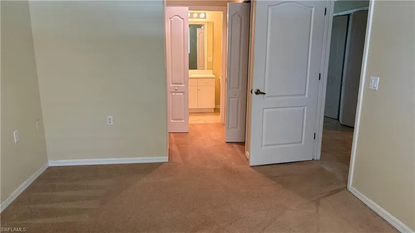 Carpeted flooring, neutral wall tones, white interior doors, and a bathroom vanity with a mirror