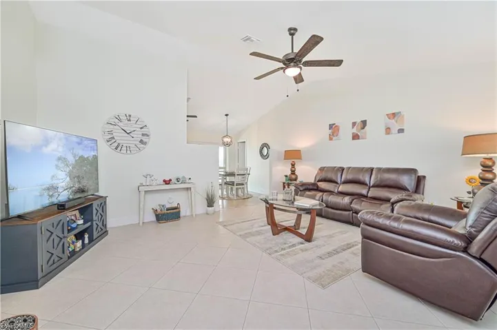Living area featuring high vaulted ceiling, a ceiling fan, and light tile patterned flooring
