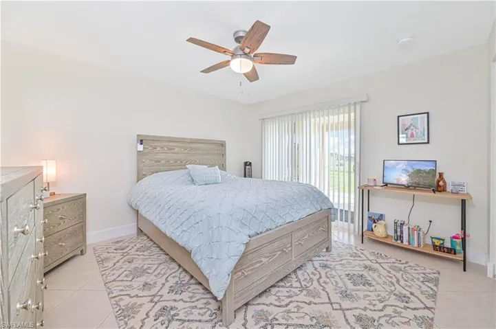 Bedroom featuring light tile patterned flooring, ceiling fan, and access to outside