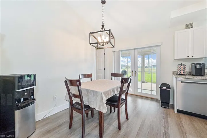 Dining room featuring a chandelier, light wood finished floors, french doors, and vaulted ceiling