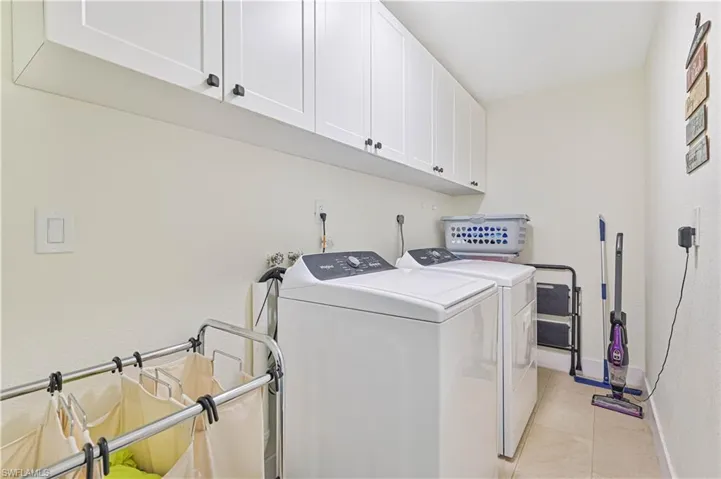 Washroom with washing machine and dryer, cabinet space, and light tile patterned flooring