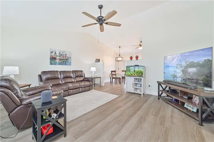 Living room with a ceiling fan, light wood-type flooring, and lofted ceiling