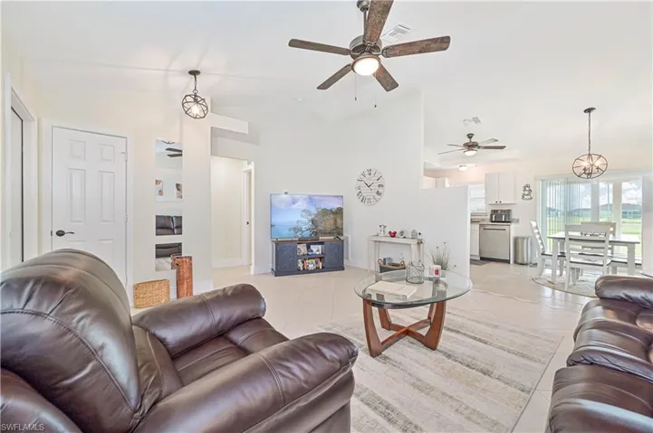 Living room with a ceiling fan, light tile patterned floors, and high vaulted ceiling