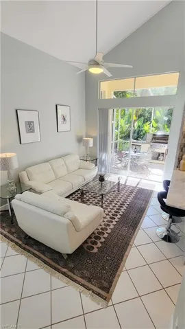 Living room with light tile patterned flooring, a ceiling fan, and high vaulted ceiling