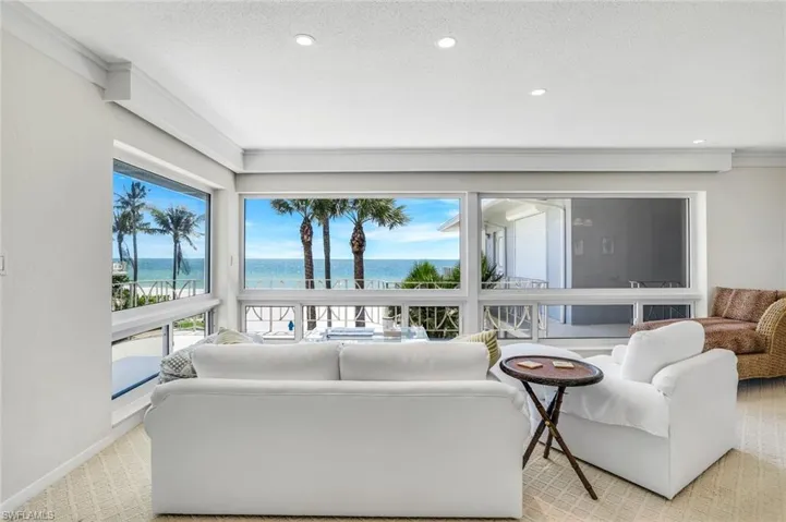 Living area featuring light colored carpet, a water view, recessed lighting, and ornamental molding