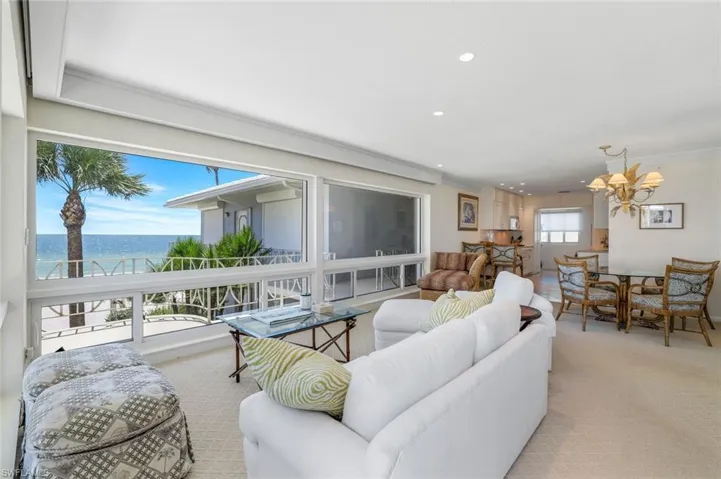 Living room with a water view, light carpet, recessed lighting, a chandelier, and ornamental molding