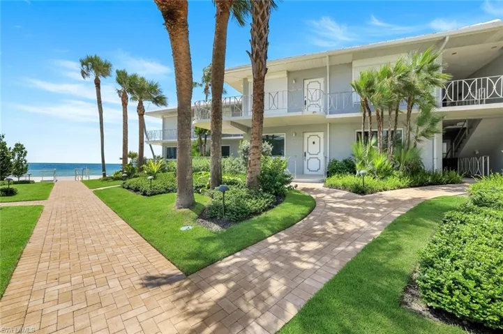 View of front of house with a balcony, a front yard, and a water view