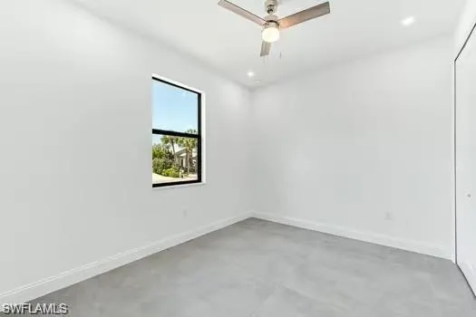 Bedroom on main entrance side with finished concrete floors and a ceiling fan