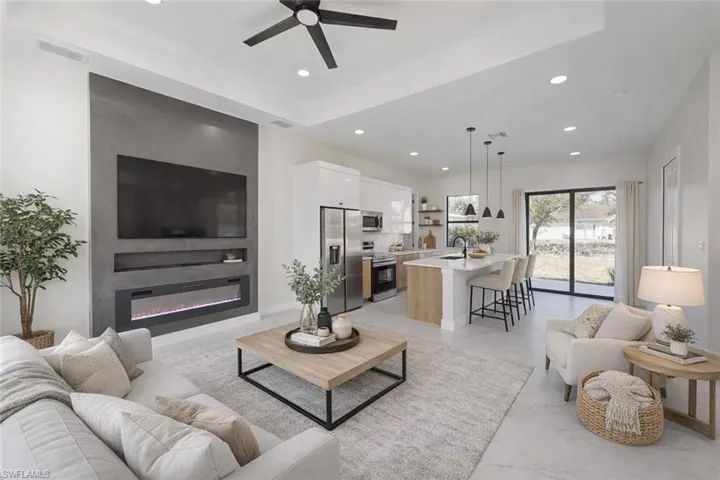 Living room with ceiling fan, a glass covered fireplace, and recessed lighting