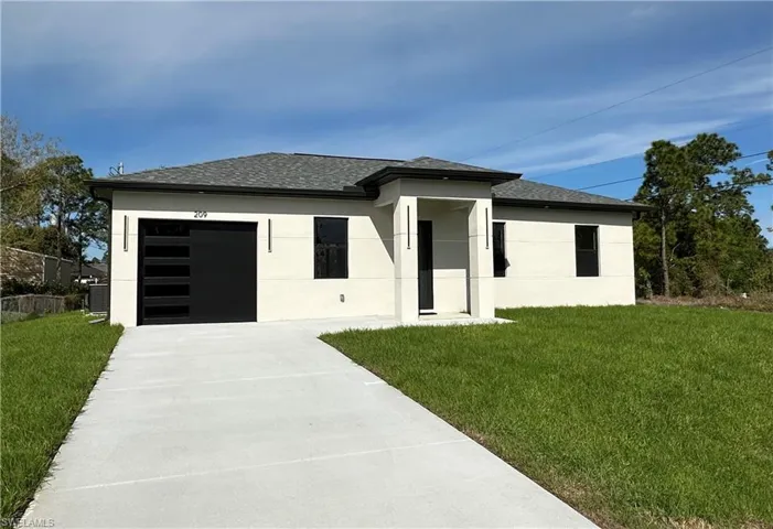 Prairie-style home featuring a front yard, stucco siding, and a garage
