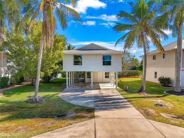 Coastal inspired home with concrete driveway, a front yard, and a carport