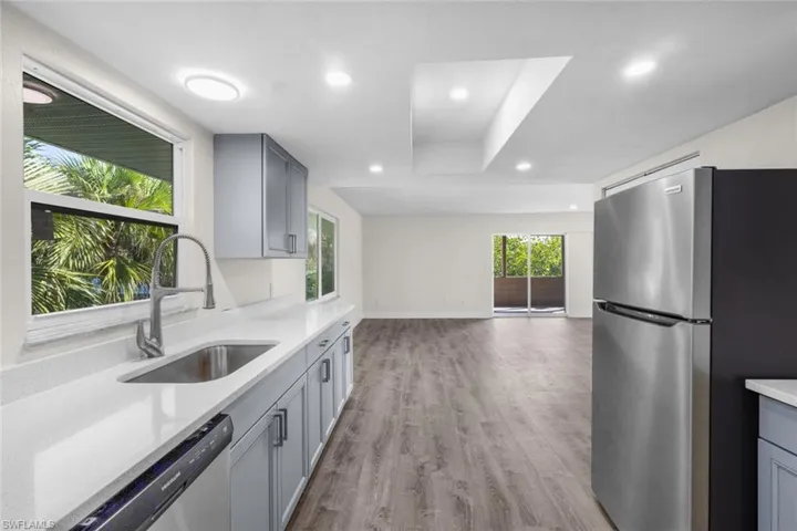 Kitchen featuring stainless steel appliances, gray cabinets, light wood-style flooring, open floor plan, and recessed lighting