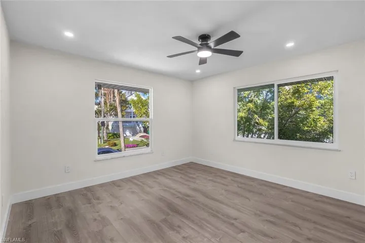 Spare room featuring wood finished floors, a ceiling fan, and recessed lighting