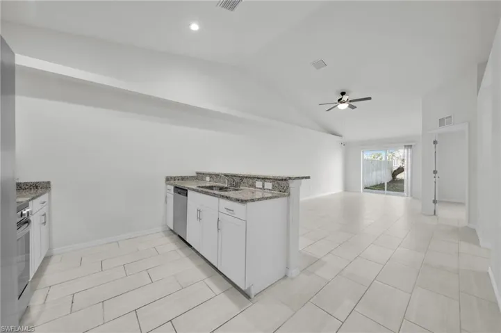 Kitchen with white cabinets, dark stone countertops, a peninsula, open floor plan, and stainless steel appliances