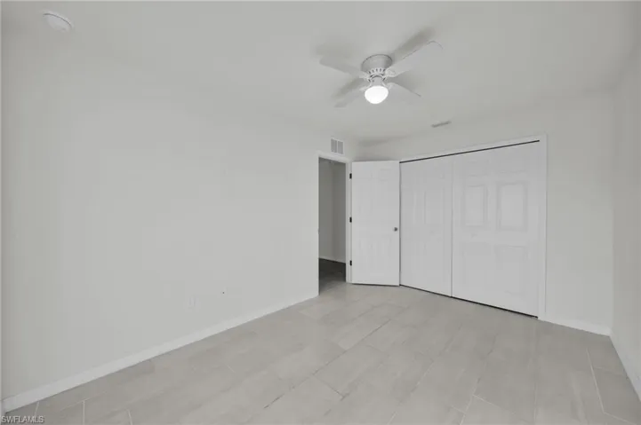 Unfurnished bedroom with ceiling fan and a closet