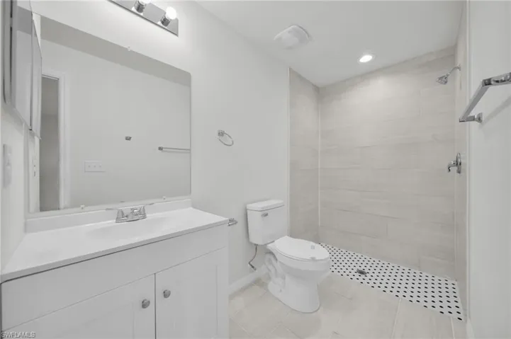 Bathroom featuring vanity, tiled shower, recessed lighting, and light tile patterned flooring