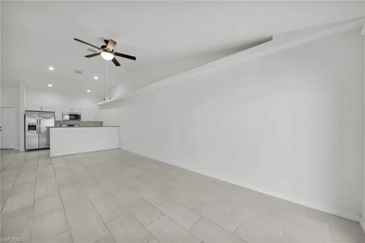 Unfurnished living room featuring vaulted ceiling, ceiling fan, and recessed lighting